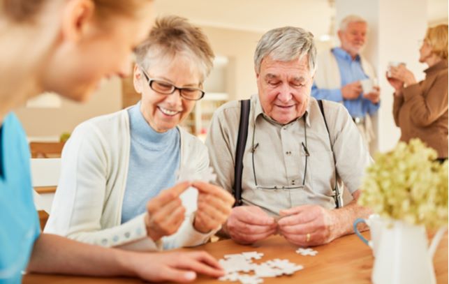 Happy seniors engaged with puzzle while socializing in senior community.